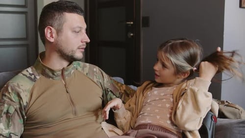 Soldier and Daughter Talking Together on Couch Indoors