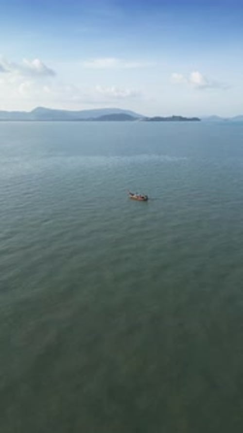 Vertical Video Drone Shot of Wooden Boat Speeding Through a Blue Tropical Lagoon