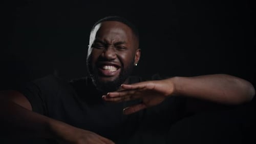 Man gesturing and speaking against dark background
