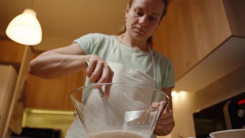 Whisking Ingredients in a Large Glass Bowl, Preparing Batter for a Baking Recipe in a Home Kitchen.