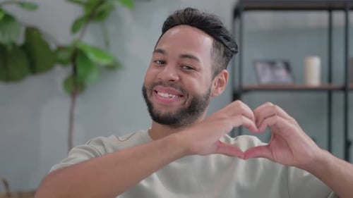 Young Adult Smiling and Making Heart Shape