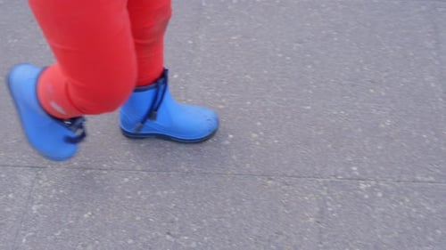 Closeup high angle view of toddler with vibrant blue shoes and red pants walk