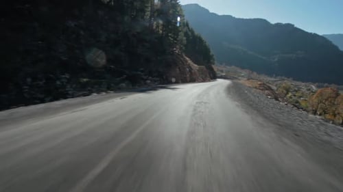 Car Mounted view of Driving on Asphalt Road between Mountains and Forest