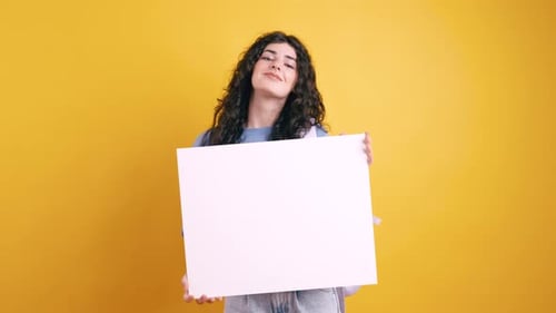 Young Student Presenting White Blank Board on Yellow Background