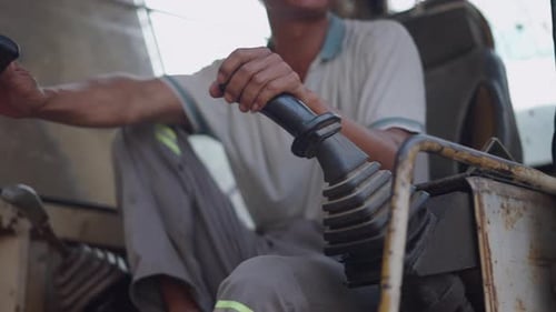 Gros plan de la main d'un ouvrier manœuvrant les commandes d'une vieille grue rouillée au Vietnam
