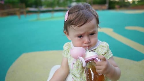 Baby Drinking From Bottle at Park