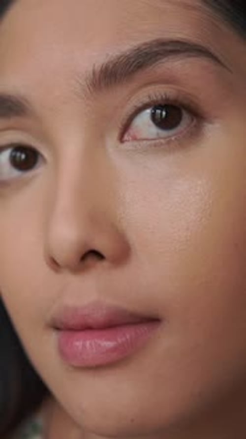 Close up footage of a young Asian woman showing her bare face before applying make up.