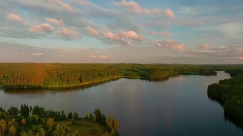 Slow aerial forested lake landscape at sunset with panoramic view