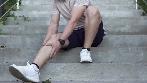 Man Massaging Leg on Concrete Urban Steps