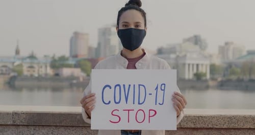 Young Woman Holds COVID-19 Sign in City
