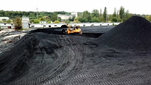 Kohleumschlag in der Fabrik. Crawler Bulldozer funktioniert. Luftbild.