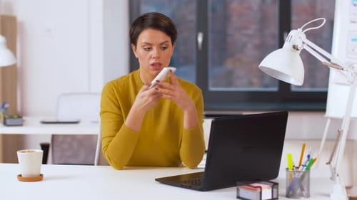 Woman Working at Desk Talking on Phone and Typing