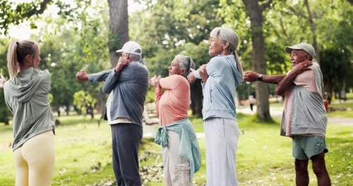 Active Seniors Stretching with Young Instructor in Park