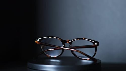 brown and green tortoiseshell round prescription glasses rotating 360 degrees against a black backgr