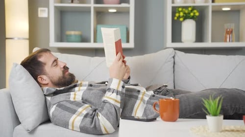 Man Reading Book on Couch at Home