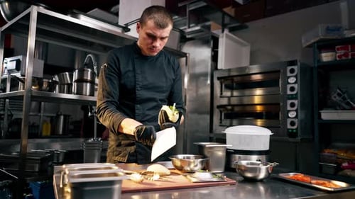 and in a Professional Kitchen a Chef in Black Uniform Puts Pita in a Paper Envelope