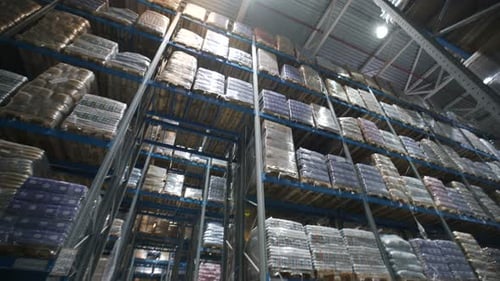 Cardboard boxes stored on metal shelves inside large warehouse logistics terminal