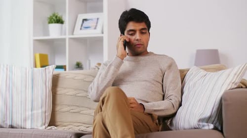 Young man on sofa talking on mobile phone