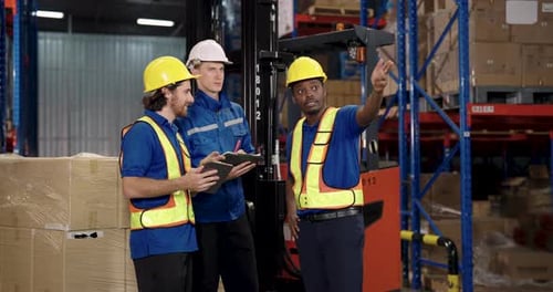 caucasian warehouse staff holding tablet while having conversation with logistic supervisor during