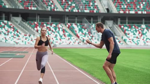 Woman Sprinter Training at the Stadium Competing in Shortdistance Running the Coach Controls the
