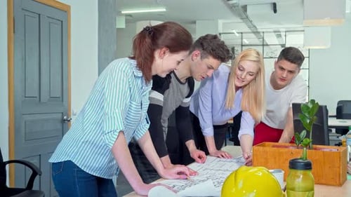 Dynamic Young Architects Collaborating on a Detailed Blueprint in a Modern Office