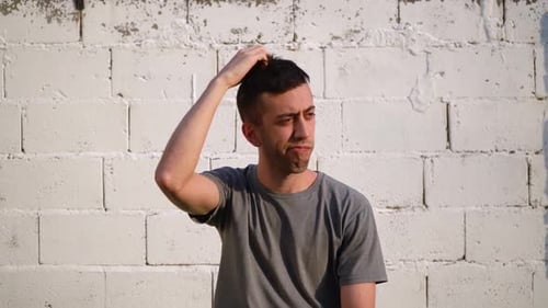 Young Man Thinking in Front of Brick Wall