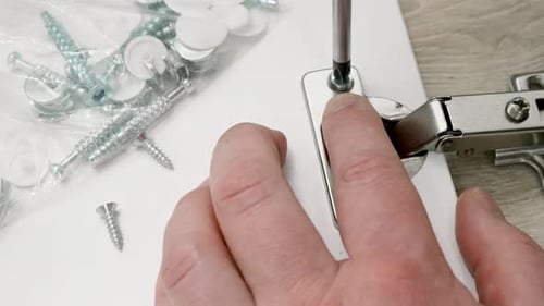 Hands attaching hinge using screw driver