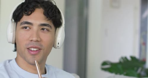 Vidéo verticale : un homme avec un casque entend et écrit des notes d'étude sous forme d'onde fusionnant avec un bloc-notes