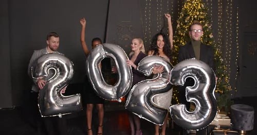 Friends Celebrating With 2023 Balloons Near Christmas Tree