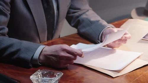 Man Examining Documents at Office Desk
