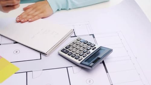 Architect calculating measurements, blueprints, notepad on desk
