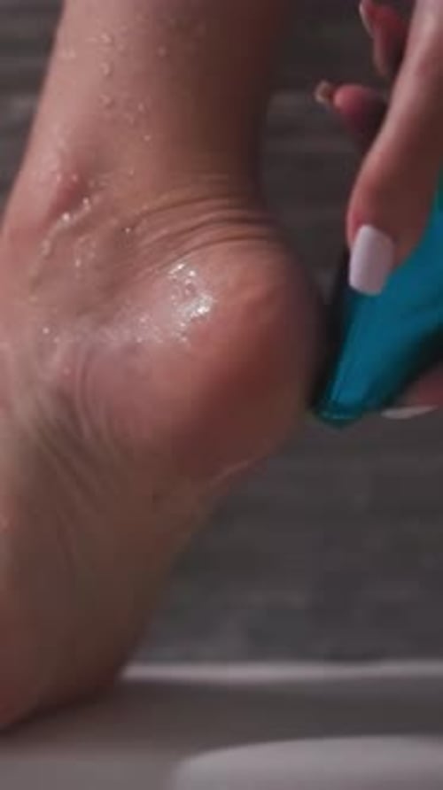 Person Exfoliates Wet Foot with Blue Foot File