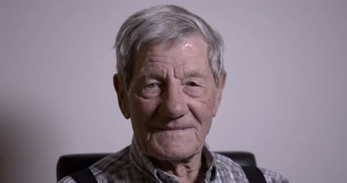 Die Augen der Senioren schließen sich, ein nachdenklicher alter kaukasischer Mann starrt in die Kamera.
