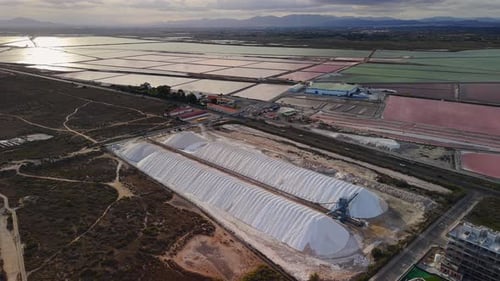 Drone View of Large Salt Piles and Colorful Evaporation Ponds Near Santa Pola Spain with Mountains