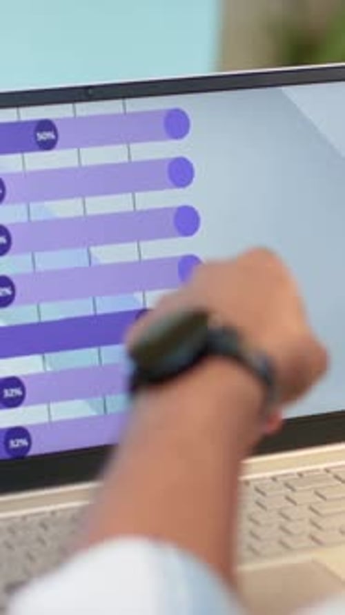 Tapping man in light-blue shirt using laptop touchscreen at table showing purple progress bars