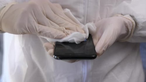 Person Cleans Smartphone with Cloth in Protective Suit