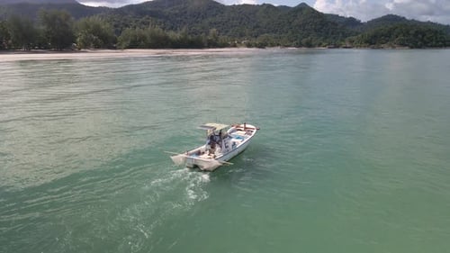 small fishing motor boat of the coast of Thai tropical island with mountains, blue sky