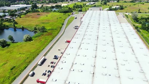 Aerial Shot of Truck with Attached Semi Trailer Leaving Industrial Warehouse Storage Building Loadin