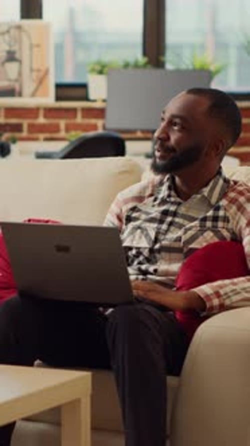 Couple Uses Laptop Together on Couch Indoors