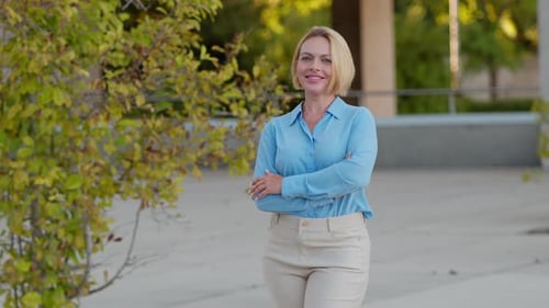 Smiling Woman Poses Outdoors with Arms Crossed