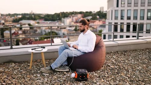 Homem de negócios conectando o cabo de carregamento à estação de energia portátil no telhado
