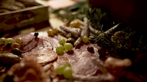 Cold cuts, grapes breadsticks and prosciutto appetizer on cutting board with rosemary herbs, Close u