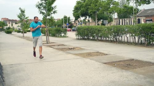 Handsome young man jogging checks pulse on smartwatch in city super slow motion