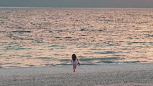 Woman Walking on Beach at Sunset