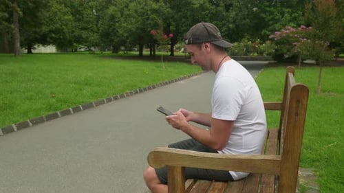 Man Using Phone While Relaxing on Park Bench