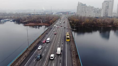 Drone flies through the rope piers of the highway bridge overlooking the car traffic