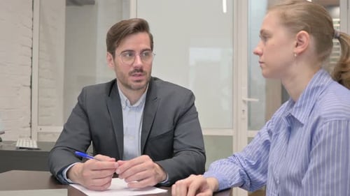 Glückliche Kollegen sprechen, während sie im Büro sitzen