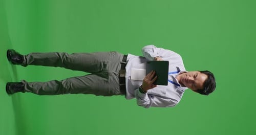 Ganzer Körper eines asiatischen Geschäftsmannes, der ein Tablet benutzt und sich im Greenscreen-Studio umschaut