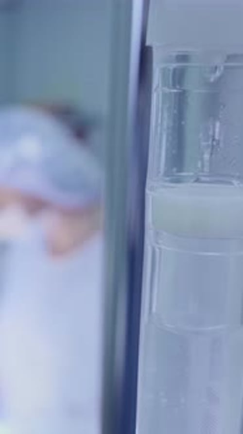 Medical Professional Preparing Intravenous Fluid in a Clinical Setting with Sterile Equipment Nearby