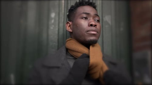 Man leaves home, opens front door, puts scarf, and steps outside in city